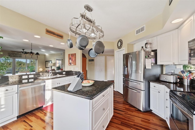 kitchen featuring dark wood-type flooring, a kitchen island, pendant lighting, white cabinets, and appliances with stainless steel finishes