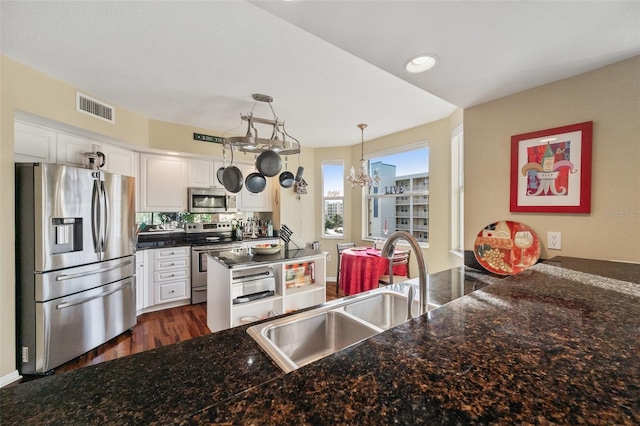 kitchen featuring hanging light fixtures, white cabinetry, sink, and stainless steel appliances