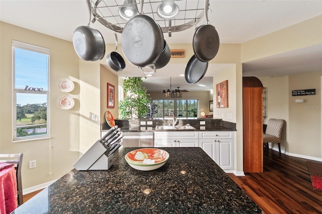 kitchen with white cabinets, an inviting chandelier, dark stone counters, and sink