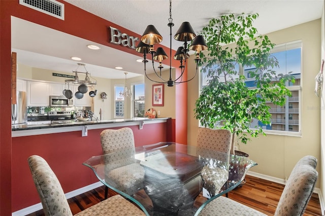 dining room featuring hardwood / wood-style flooring, a notable chandelier, and sink