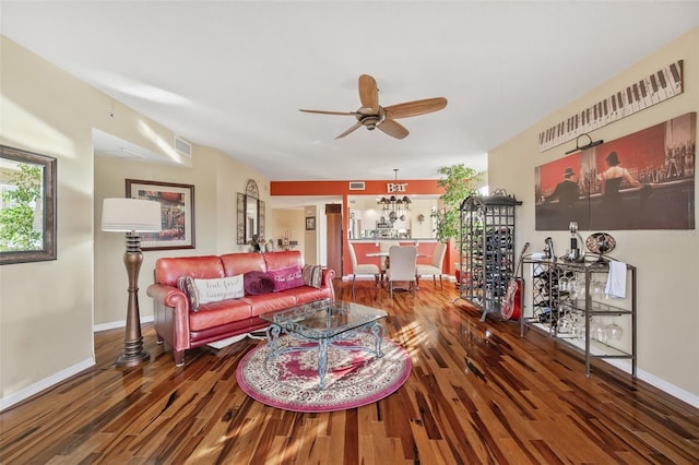 living room featuring ceiling fan with notable chandelier and dark hardwood / wood-style flooring