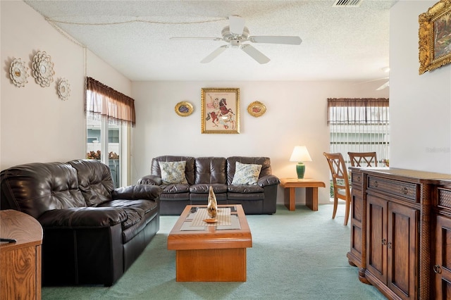 carpeted living room with a textured ceiling and ceiling fan