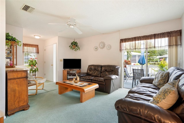 living room featuring a textured ceiling, ceiling fan, and carpet