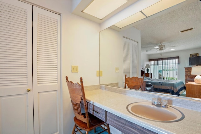 bathroom with a textured ceiling, ceiling fan, and vanity