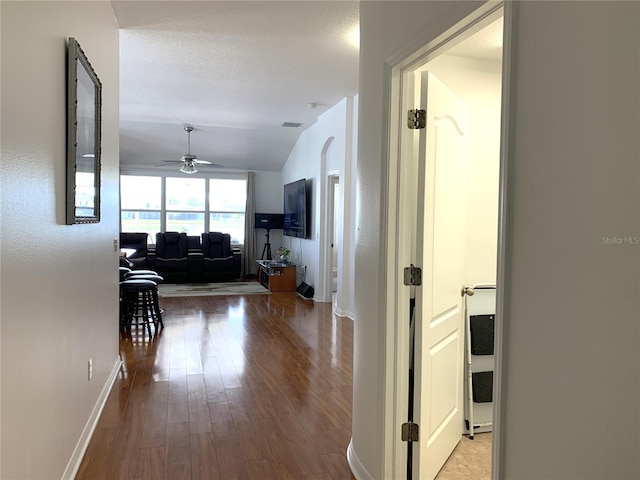 hallway featuring wood-type flooring, a textured ceiling, and lofted ceiling