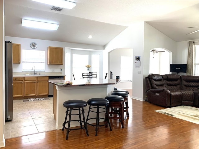 kitchen with sink, stainless steel appliances, a kitchen breakfast bar, light hardwood / wood-style floors, and a kitchen island