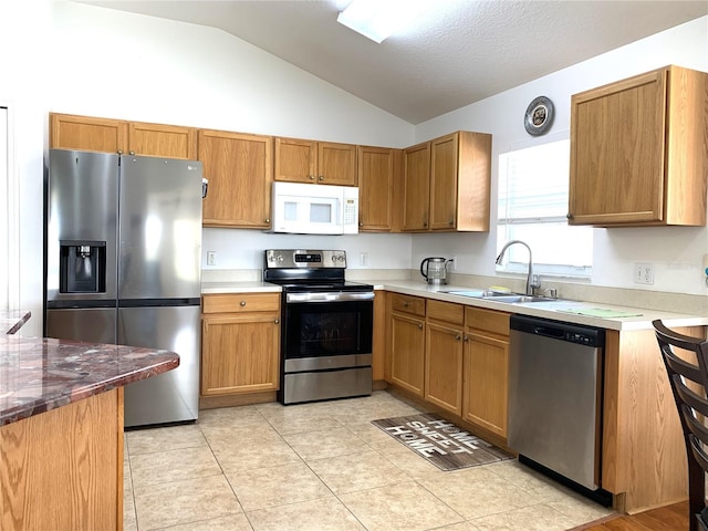 kitchen with light tile patterned floors, sink, appliances with stainless steel finishes, and vaulted ceiling