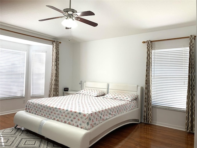 bedroom featuring ceiling fan, dark wood-type flooring, and multiple windows