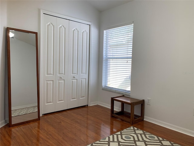 unfurnished bedroom with multiple windows, a closet, hardwood / wood-style floors, and lofted ceiling