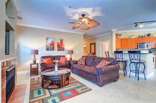 tiled living room featuring track lighting, ceiling fan, and crown molding