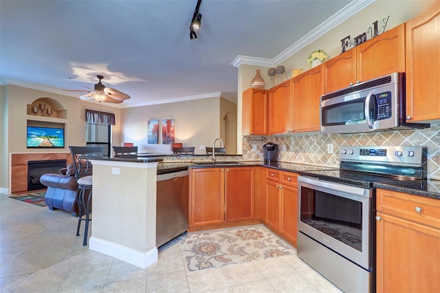 kitchen featuring sink, ornamental molding, light tile patterned flooring, kitchen peninsula, and stainless steel appliances