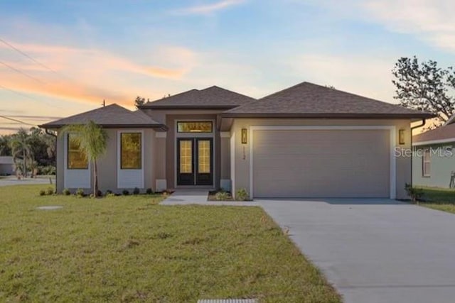 prairie-style house featuring a garage and a yard