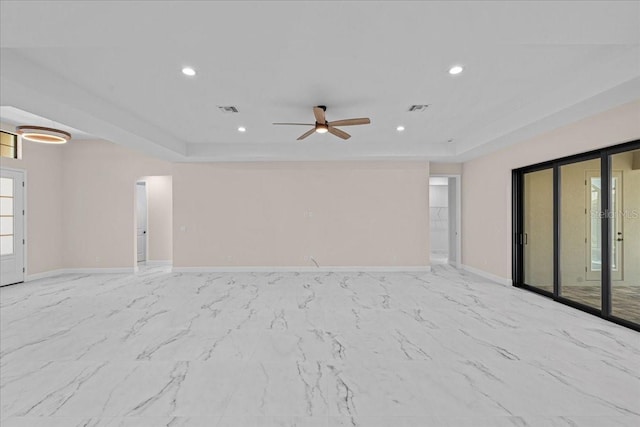 empty room featuring a raised ceiling and ceiling fan