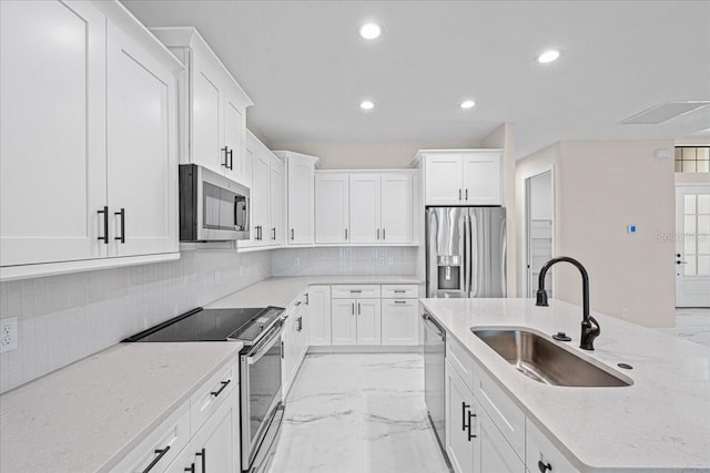 kitchen featuring white cabinetry, sink, stainless steel appliances, tasteful backsplash, and light stone counters