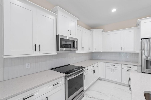 kitchen with decorative backsplash, white cabinetry, light stone counters, and appliances with stainless steel finishes