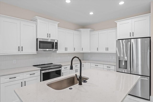 kitchen featuring light stone counters, white cabinetry, sink, and appliances with stainless steel finishes