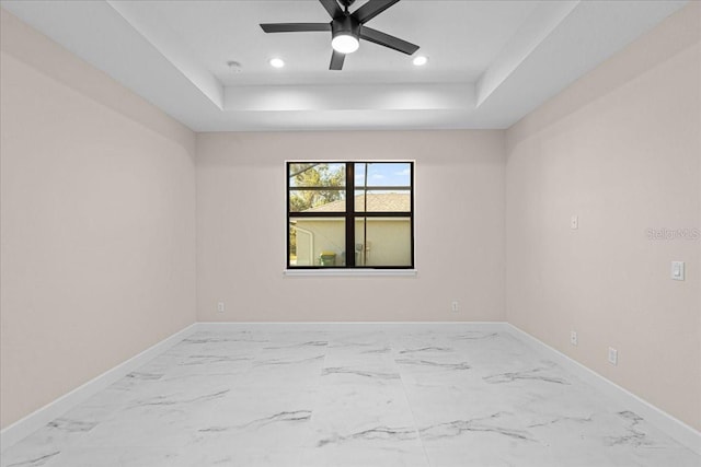 empty room featuring a tray ceiling and ceiling fan