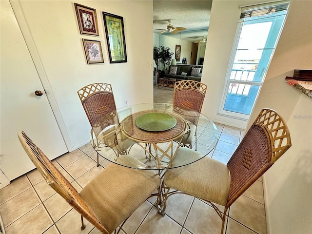 tiled dining space with a textured ceiling and ceiling fan