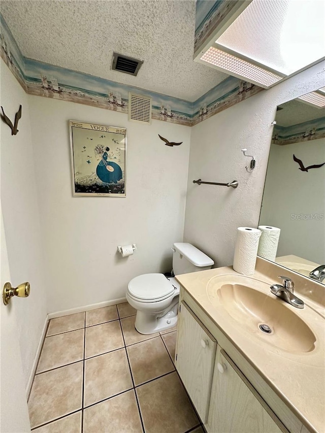 bathroom with vanity, toilet, tile patterned flooring, and a textured ceiling