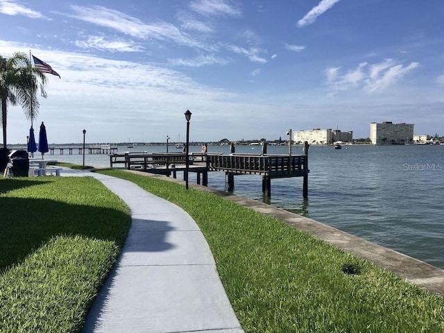 dock area with a lawn and a water view