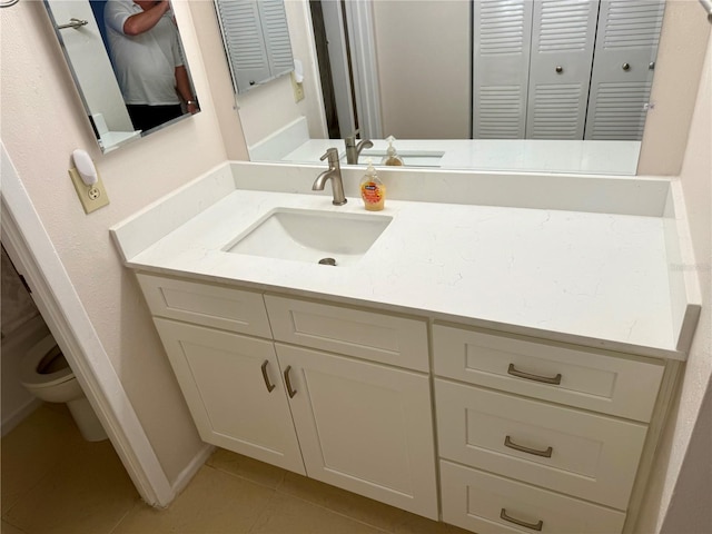 bathroom featuring tile patterned flooring, vanity, a closet, and toilet