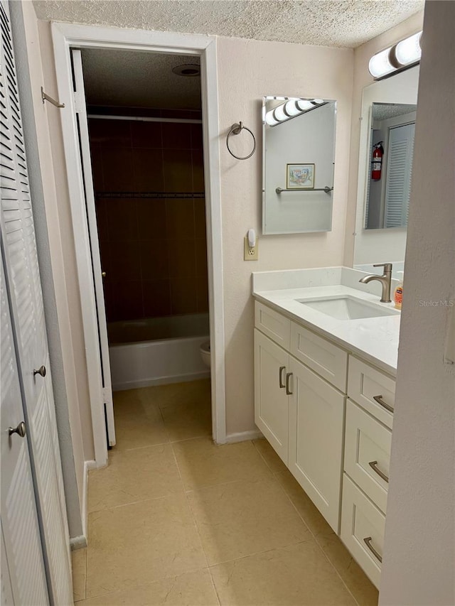 bathroom featuring a textured ceiling, vanity, toilet, tile patterned floors, and baseboards
