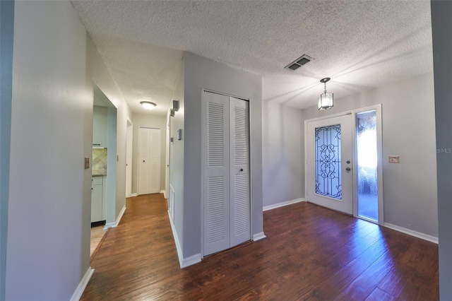 foyer entrance featuring dark hardwood / wood-style flooring, a textured ceiling, and an inviting chandelier