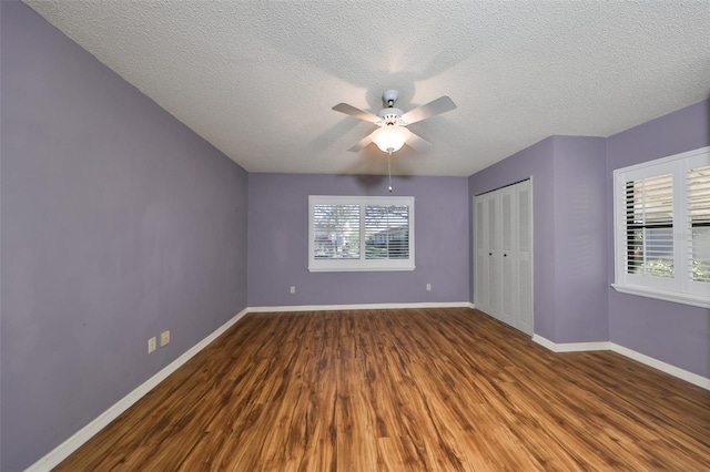 unfurnished bedroom with hardwood / wood-style flooring, ceiling fan, a textured ceiling, and a closet