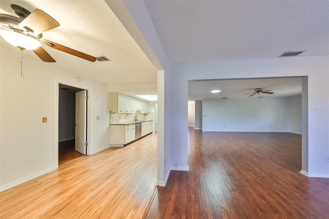 empty room with ceiling fan, sink, a textured ceiling, and light hardwood / wood-style flooring