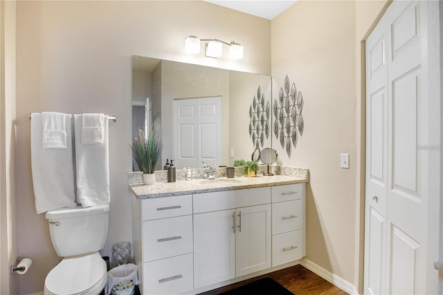 bathroom with hardwood / wood-style flooring, vanity, and toilet