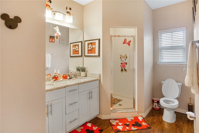 bathroom with hardwood / wood-style floors, vanity, toilet, and a shower with shower door