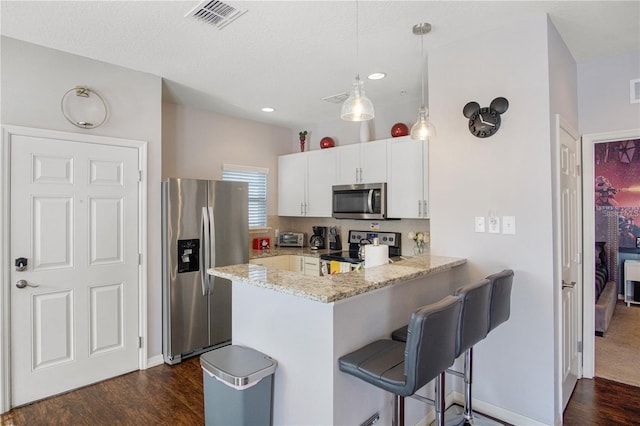 kitchen with light stone countertops, stainless steel appliances, kitchen peninsula, pendant lighting, and white cabinets