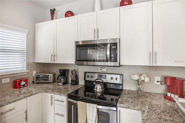 kitchen featuring white cabinets, appliances with stainless steel finishes, and light stone countertops