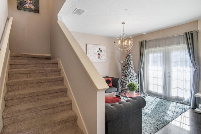 stairway featuring a textured ceiling and an inviting chandelier