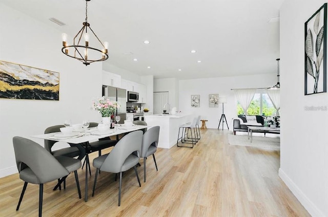 dining room featuring light wood-type flooring and an inviting chandelier