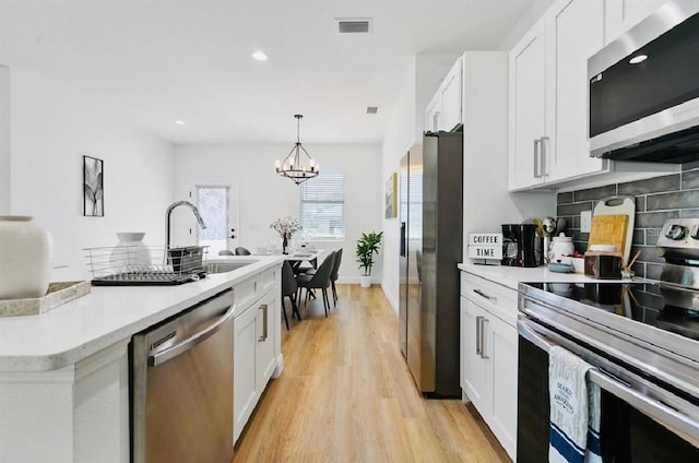 kitchen featuring white cabinets, pendant lighting, stainless steel appliances, and sink