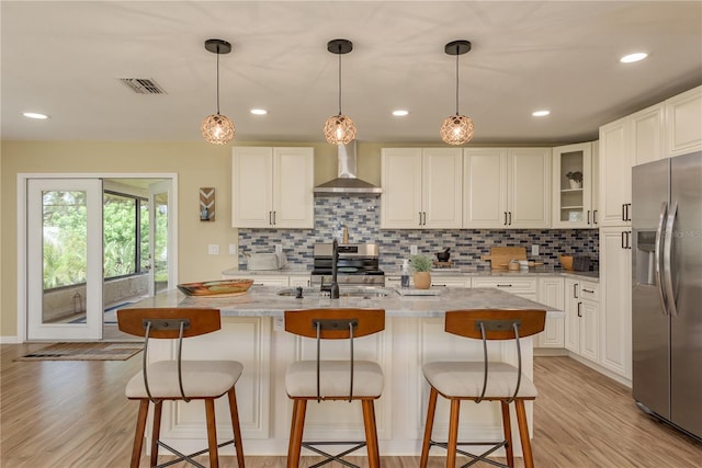 4514 Dewey Dr, New Port Richey, FL 34652 - kitchen with appliances with stainless steel finishes, wall chimney range hood, decorative backsplash, light wood-style flooring, and white cabinets