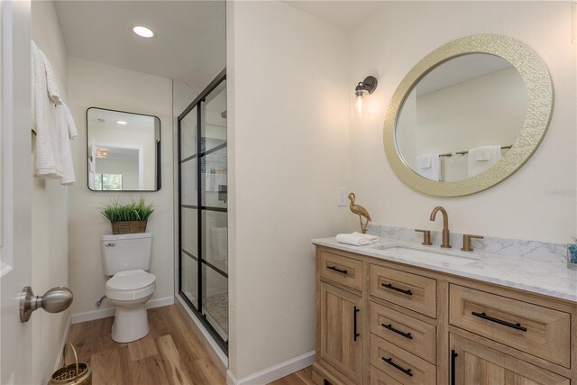 4514 Dewey Dr, New Port Richey, FL 34652 - bathroom with wood finished floors, a shower with shower door, toilet, vanity, and recessed lighting