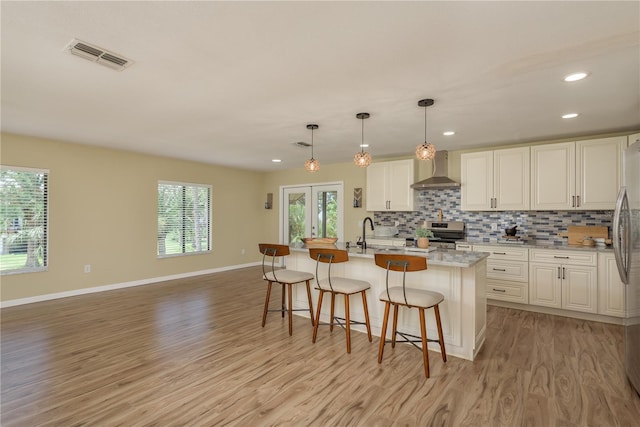 4514 Dewey Dr, New Port Richey, FL 34652 - kitchen featuring wall chimney range hood, appliances with stainless steel finishes, light wood finished floors, white cabinets, and recessed lighting
