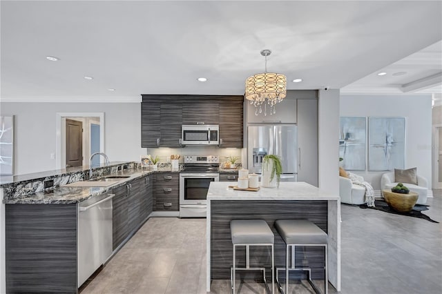 kitchen featuring a kitchen bar, stainless steel appliances, crown molding, sink, and pendant lighting