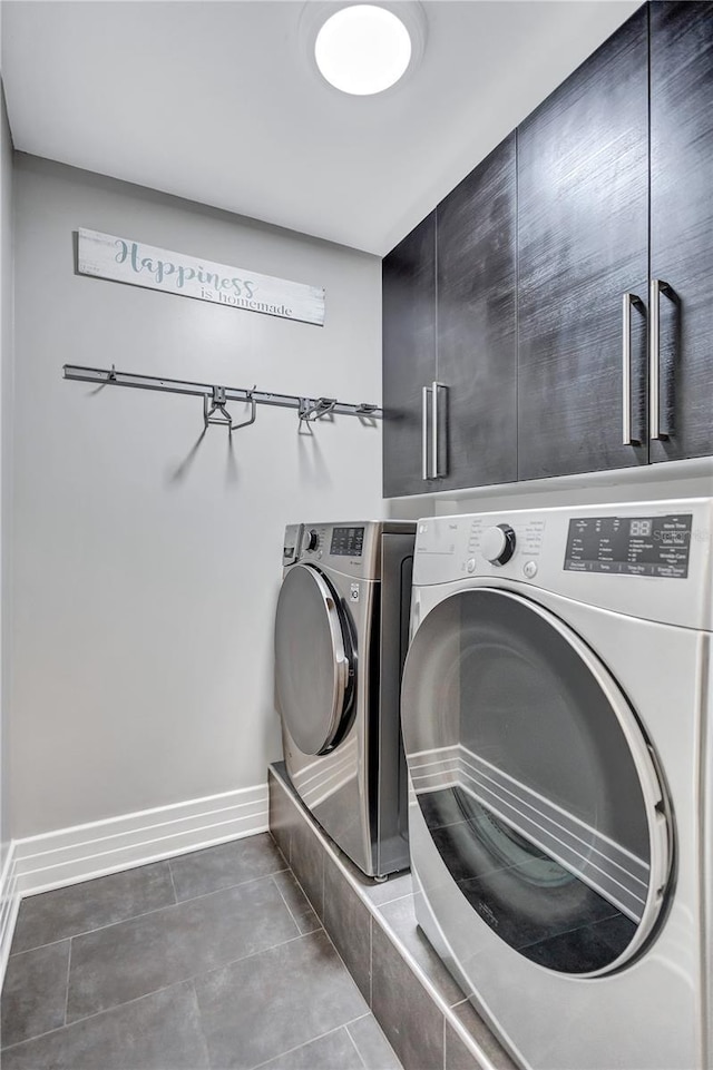 laundry area featuring washer and dryer, cabinets, and dark tile patterned floors