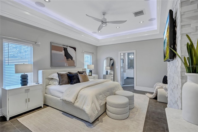 bedroom featuring tile patterned flooring, ceiling fan, a raised ceiling, and connected bathroom