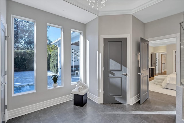 interior space with ornamental molding, dark tile patterned floors, a wealth of natural light, and a notable chandelier