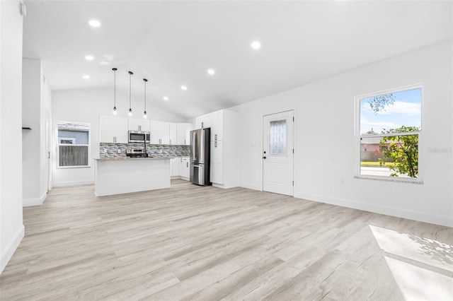 unfurnished living room with vaulted ceiling and light wood-type flooring