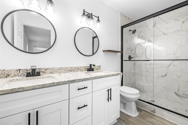 bathroom with hardwood / wood-style floors, vanity, an enclosed shower, and toilet