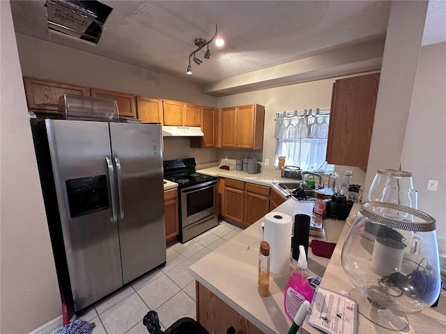 kitchen with appliances with stainless steel finishes, track lighting, a textured ceiling, sink, and light tile patterned flooring