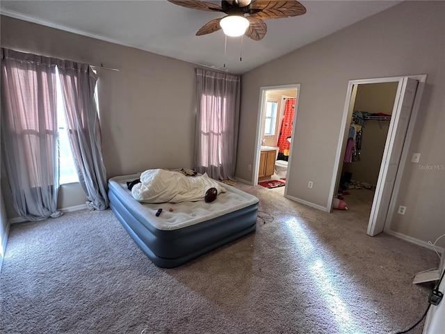 carpeted bedroom with vaulted ceiling, ceiling fan, a spacious closet, connected bathroom, and a closet