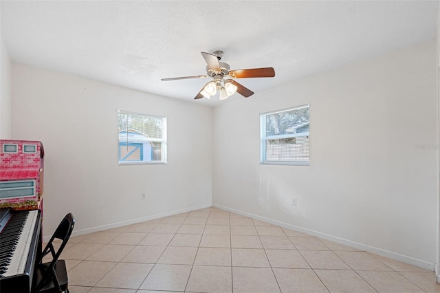 tiled empty room with ceiling fan and plenty of natural light