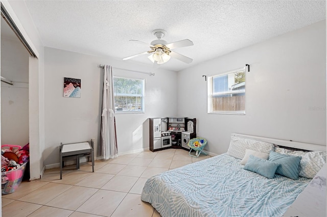 tiled bedroom with a closet, ceiling fan, and a textured ceiling