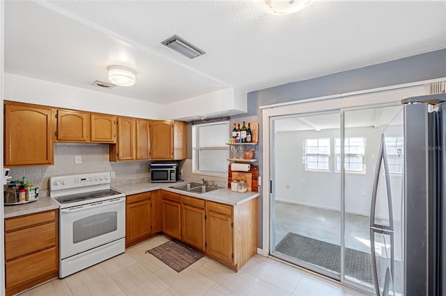 kitchen with stainless steel appliances, a textured ceiling, sink, and tasteful backsplash